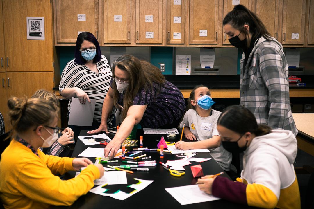 Four middle school girls work on creating paper models of shapes like pyramids, 立方体和十二面体. 玛格丽特·沃茨博士. 芭芭拉·詹宁斯·赫尔佐格, 谁在十大网络娱乐平台注册教数学, 和Bailee back, 初级基础教育和特殊教育专业. They are in one of the classrooms in Doane's Lied science building. 